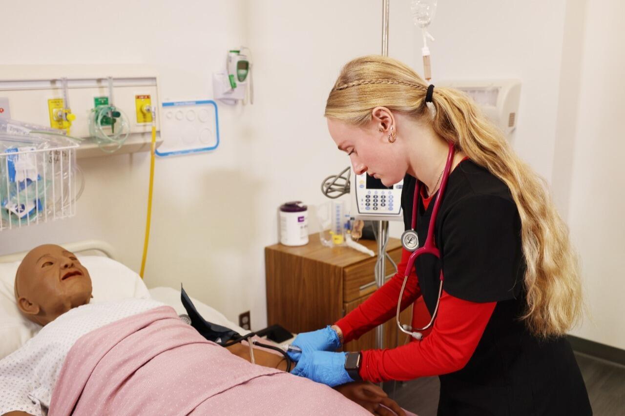 Female nursing student practicing on patient simulator